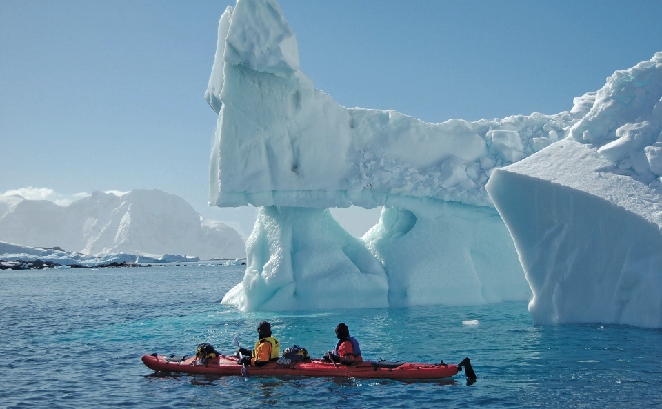 Passengers marvel at a massive iceberg floating nearby while kayaking in Greenland. Photo credit: Keith Perry