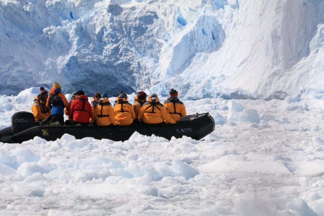Quark Expeditions passengers zodiac cruise the ice-choked waters of Cierva Cove, beneath sprawling icebergs.