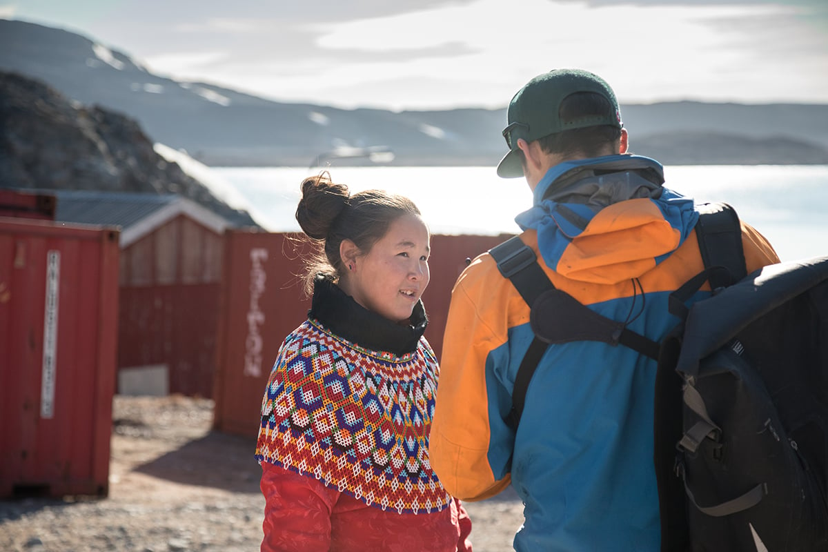 Bella Brandt, wearing the Greenlandic national costume, catches up with Quark Expeditions guide Lauritz Schönfeld in Ittoqqortoormiit. Photo by Acacia Johnson
