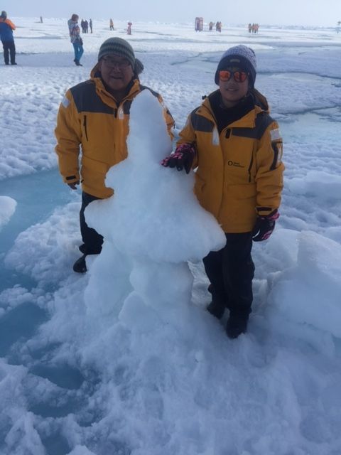 David Serkoak and a fellow passenger stand on the ice at 90° North beside an inukshuk they built while on expedition. Photo credit: David Serkoak