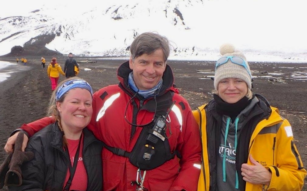 Passenger Bethany Eighmy, Quark Expeditions team member/ornithologist Santiago de la Vega, and passenger Kim Eighmy hiking and exploring Antarctica on a shore landing.