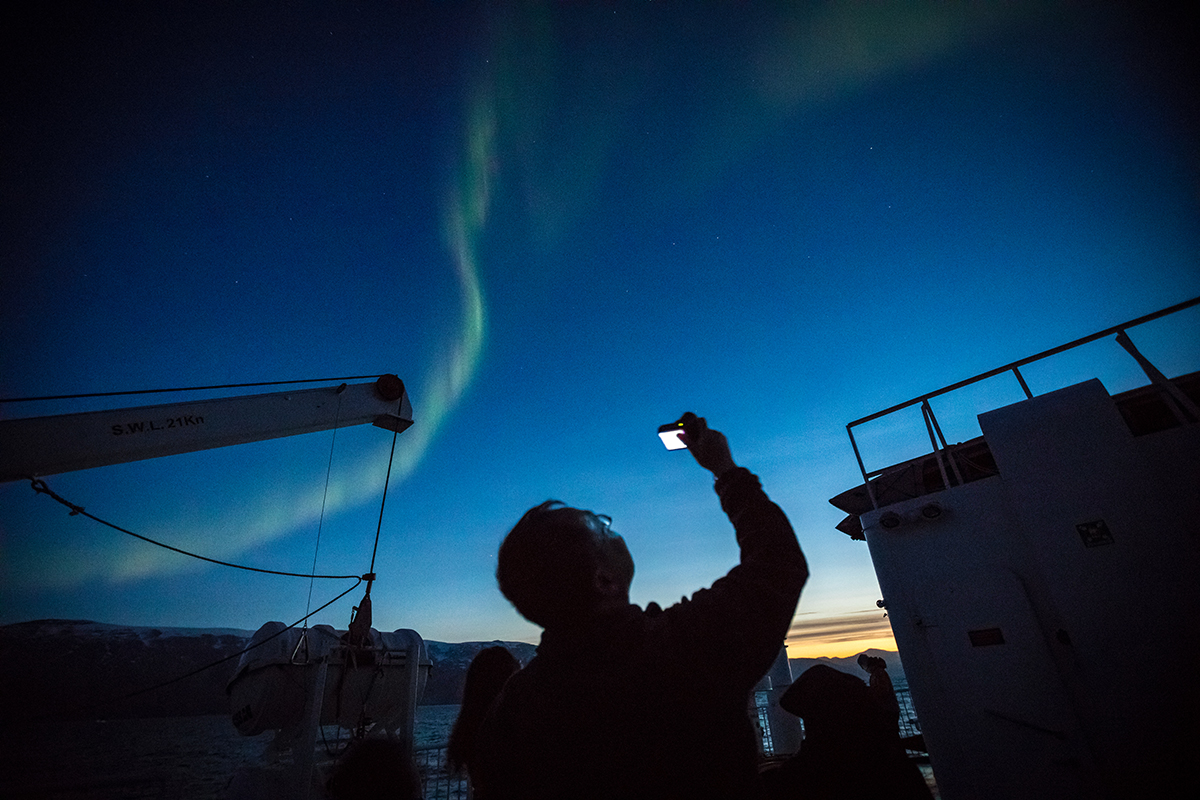 A Quark Expeditions passenger photographs the aurora from the top deck of the ship. Photo by Acacia Johnson