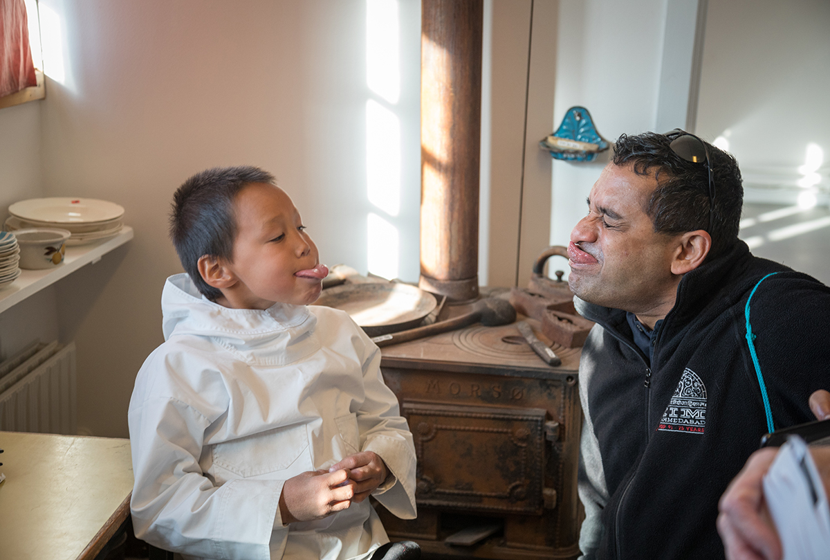 Quark Expeditions passenger interacts with a Greenlandic boy. Photo by Acacia Johnson