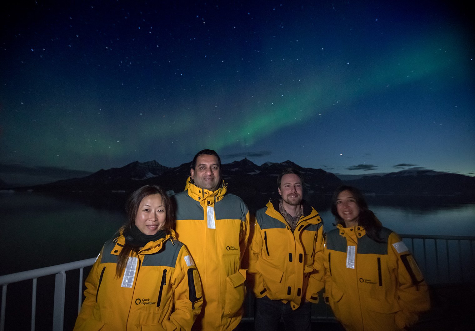 A group of Quark Expeditions guests bask in the glow of the Northern Lights.