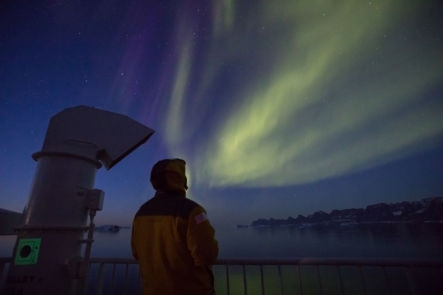 A Quark Expeditions guests watches with awe the Northern Lights from the deck of a polar vessel.
