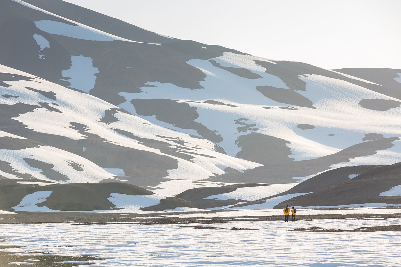 Two Quark Expeditions guests hiking in snowy East Greenland.