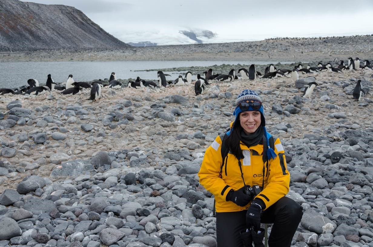 Nadine Ponte sits surrounded by penguins in Antarctica