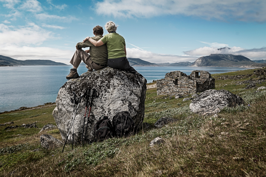 A couple enjoy the view from the shores of a Greenland fjord.