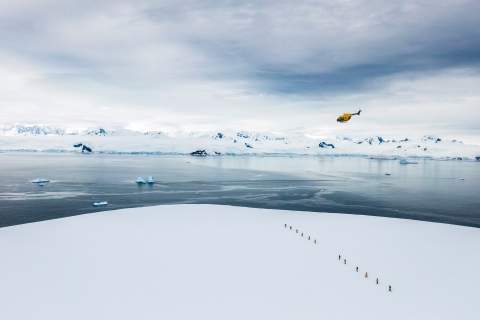 Rendering of helicopter flying away from a group of adventurers trekking in the Antarctic snow.