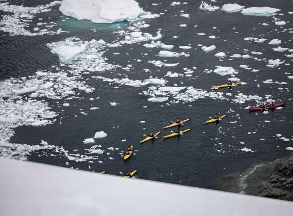 Passengers kayaking in icy landscape